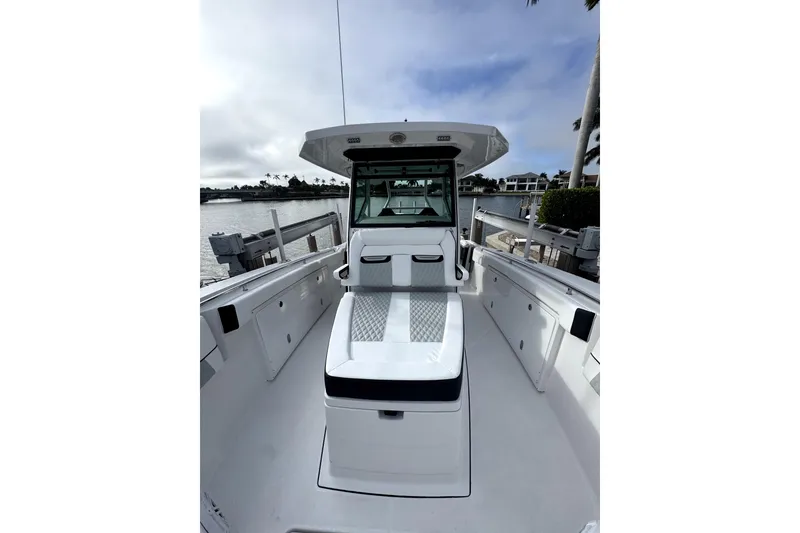 Slide: The Image of 2026 Blackfin 332 CC boat interior with seating, docked by waterfront homes. - 10