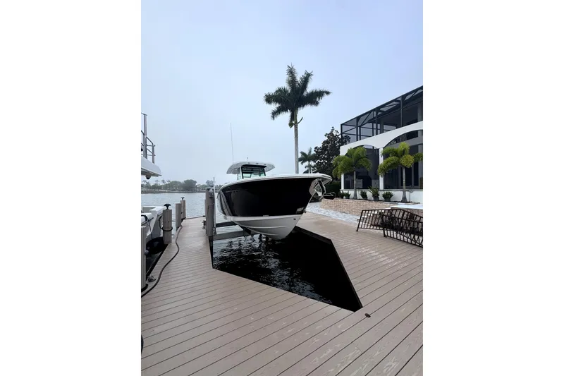 Slide: The Image of 2026 Blackfin 332 CC boat docked by a modern waterfront home. - 4