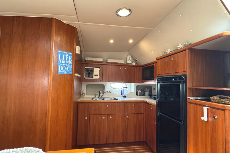 Slide: The Image of Interior of 1998 Tiara Yachts 4100 Open, featuring a wooden kitchen with modern amenities. - 11