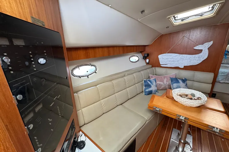 Slide: The Image of 1998 Tiara Yachts 4100 Open interior with beige seating, wooden table, and nautical decor. - 7
