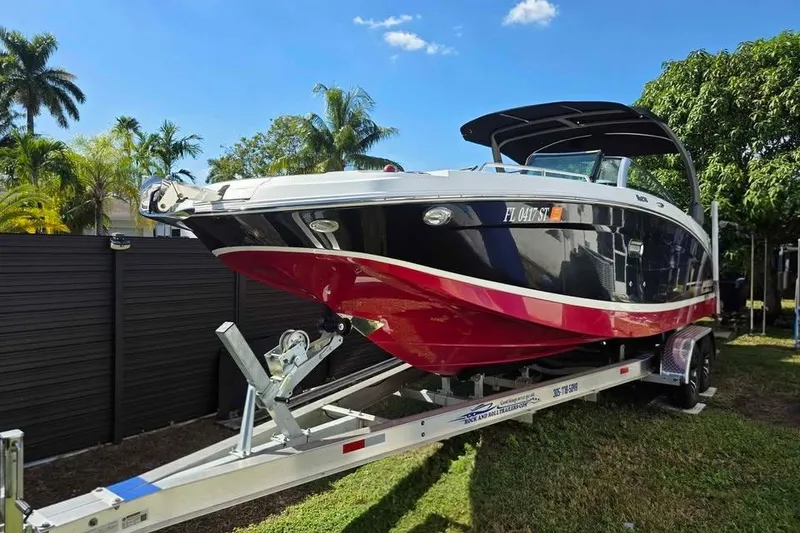 The Image of 2020 Four Winns HD270 RS boat on trailer, black and red design, sunny day. - 0