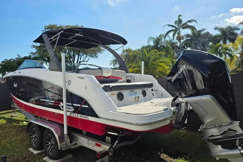 Slide: The Image of 2020 Four Winns HD270 RS boat on trailer, surrounded by tropical trees. - 2