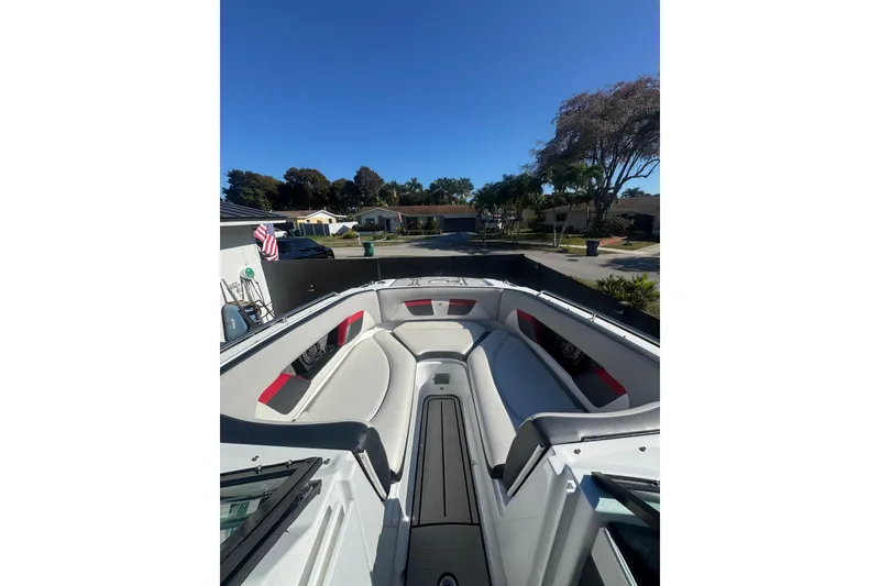Slide: The Image of 2020 Four Winns HD270 RS boat interior with seating, parked in a residential area. - 23