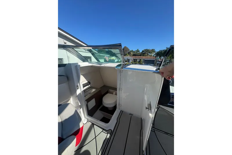 Slide: The Image of 2020 Four Winns HD270 RS boat interior with open door revealing compact bathroom. - 39