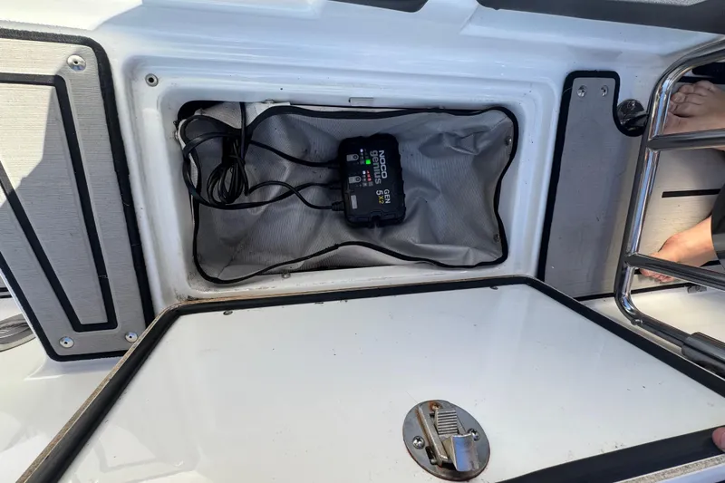 Slide: The Image of Open storage compartment on 2020 Four Winns HD270 RS boat with NOCO Genius charger inside. - 56
