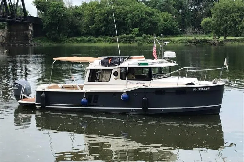 The Image of 2022 Ranger Tugs R-27 boat on a calm river with lush greenery. - 0