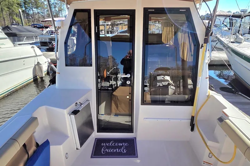 Slide: The Image of 2022 Ranger Tugs R-27 boat deck with covered equipment, docked on calm water. - 10