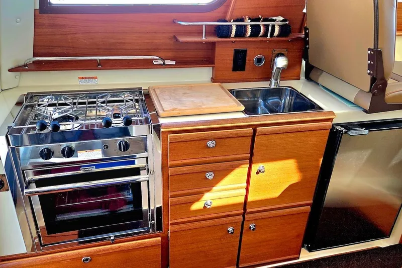 Slide: The Image of 2022 Ranger Tugs R-27 interior with wooden table and beige seating. - 17