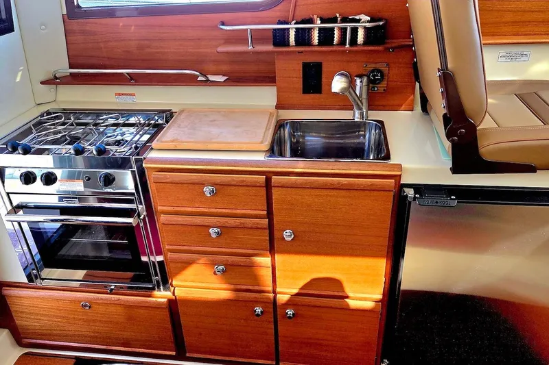 Slide: The Image of Interior view of 2022 Ranger Tugs R-27 boat with kitchen and seating area. - 18