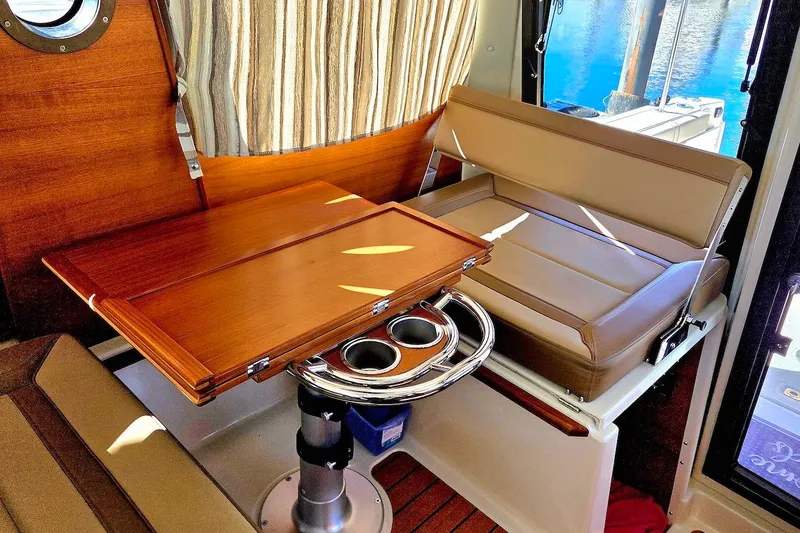 Slide: The Image of 2022 Ranger Tugs R-27 helm with Garmin navigation, wood accents, and cushioned seating. - 20