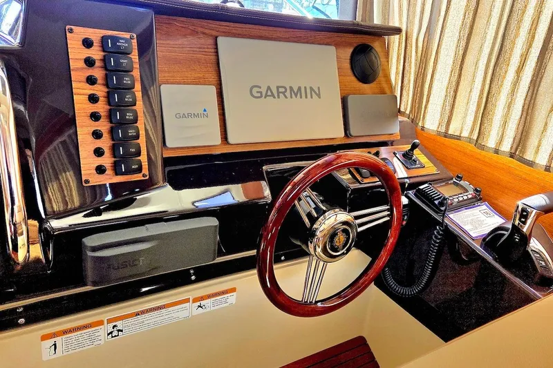 Slide: The Image of 2022 Ranger Tugs R-27 interior helm seat with beige upholstery and wooden accents. - 25