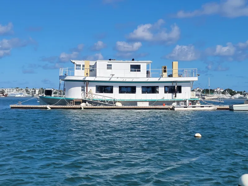 Slide: The Image of Custom 2003 floating home on water, blue sky, and distant boats. - 1