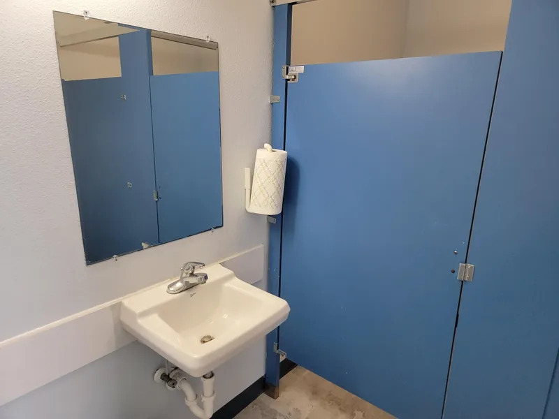 Slide: The Image of Small bathroom with blue stall, sink, mirror, and paper towel holder in a floating home. - 11