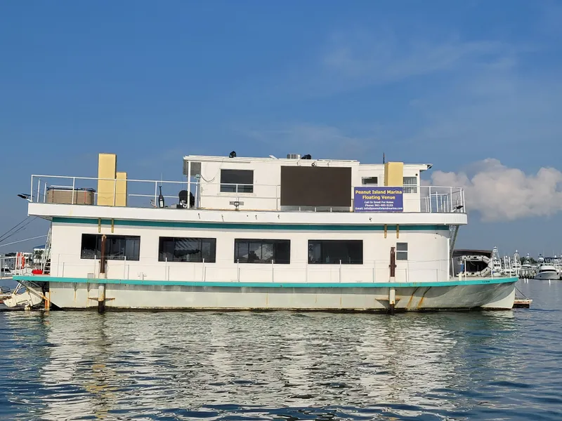 Slide: The Image of Custom 2003 floating home on water, featuring multiple windows and upper deck, under clear blue sky. - 2