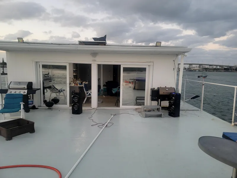 Slide: The Image of Floating home with spacious deck, outdoor seating, and grills, set against a cloudy sky. - 21