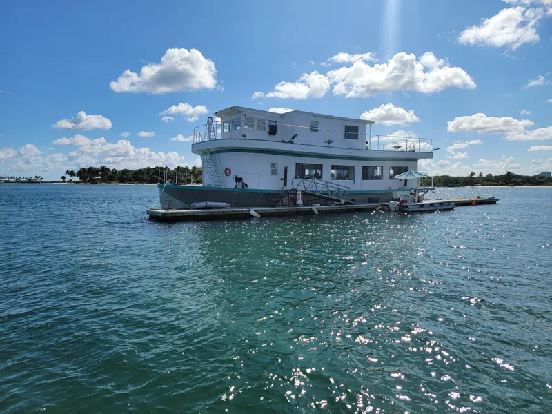 Slide: The Image of Custom 2003 floating home on serene water under a bright blue sky with fluffy clouds. - 3
