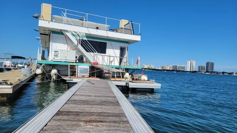 Slide: The Image of Floating home docked on water with city skyline in background, clear blue sky. - 33