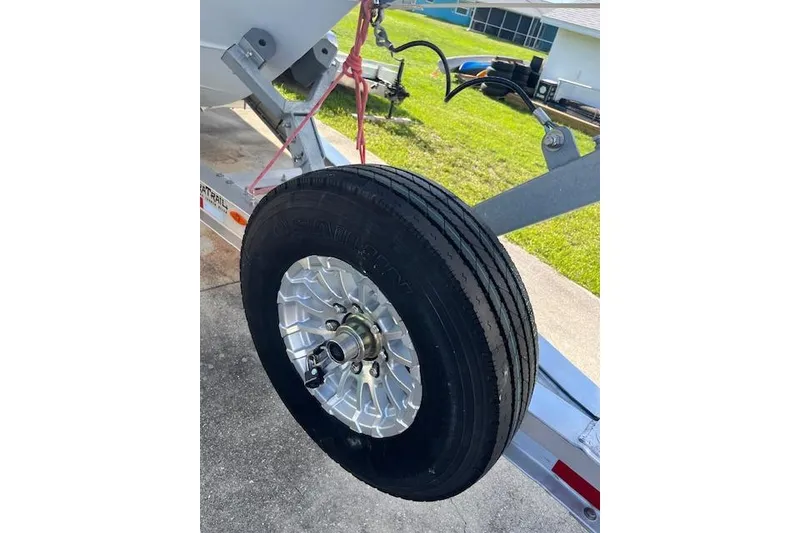 Slide: The Image of Trailer wheel of a 2024 Contender 32 ST boat, parked on concrete. - 16