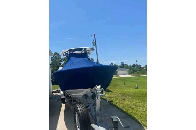 Slide: The Image of 2024 Contender 32 ST boat with blue cover on trailer, parked outdoors. - 2