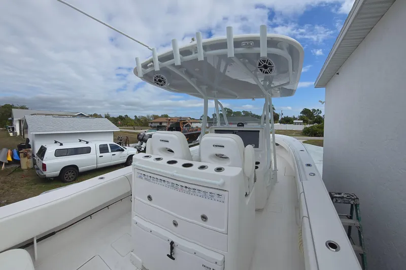Slide: The Image of 2024 Contender 32 ST boat with center console and T-top, parked near a white truck. - 24