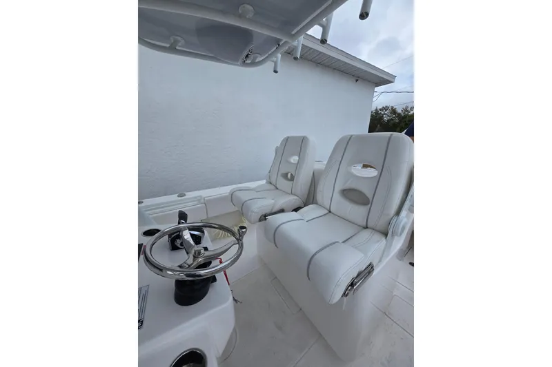 Slide: The Image of 2024 Contender 32 ST boat interior with white captain's chairs and steering wheel. - 27