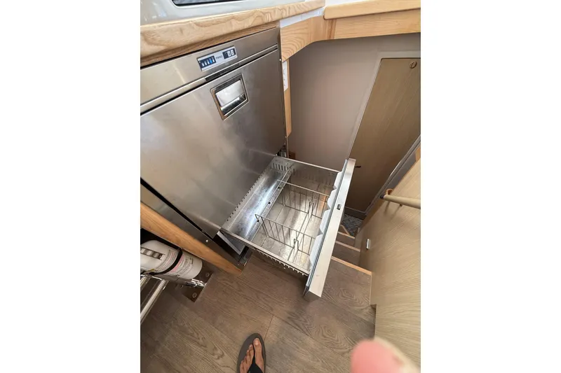 Slide: The Image of 2024 Seawind 1370 yacht interior with open stainless steel dishwasher drawer. - 19