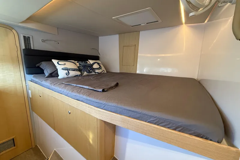 Slide: The Image of 2024 Seawind 1370 cabin interior with cozy bed and nautical-themed pillows. - 28