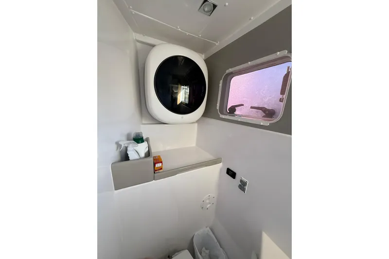 Slide: The Image of 2024 Seawind 1370 interior with compact washing machine and window view. - 53