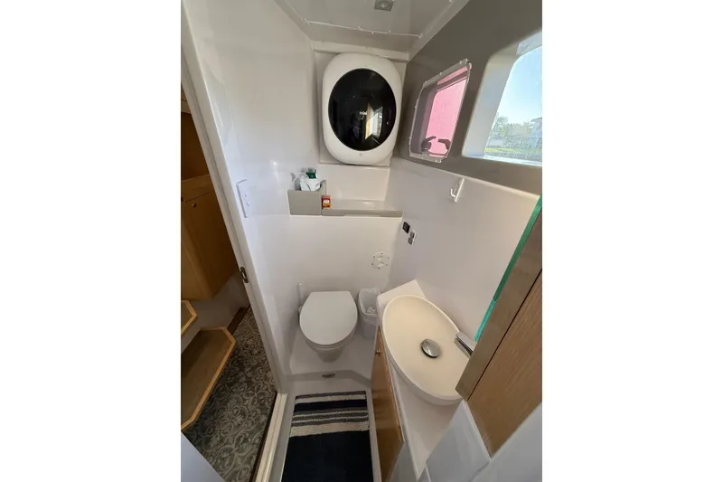 Slide: The Image of 2024 Seawind 1370 yacht bathroom with toilet, sink, and washing machine. - 54