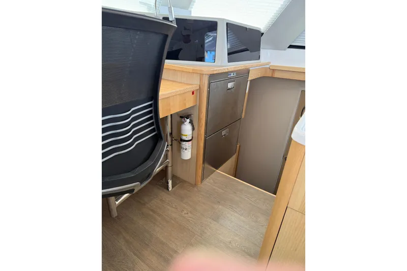 Slide: The Image of 2024 Seawind 1370 interior with modern design, featuring a chair, drawers, and fire extinguisher. - 65