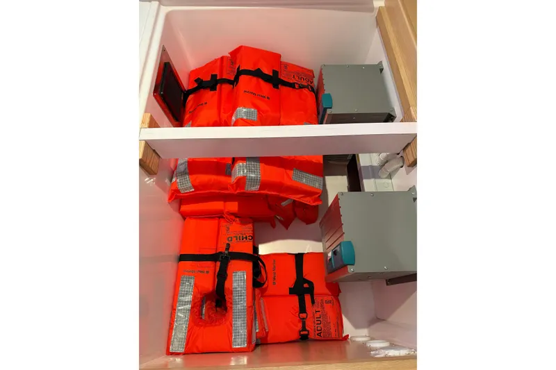 Slide: The Image of Storage compartment with orange life jackets on a 2024 Seawind 1370 catamaran. - 70