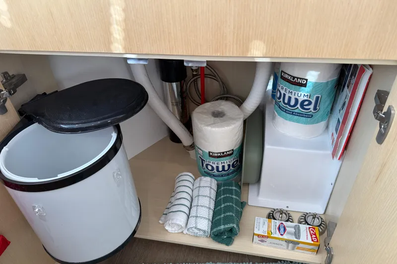 Slide: The Image of Under-sink storage in 2024 Seawind 1370 yacht with paper towels and cleaning supplies. - 75