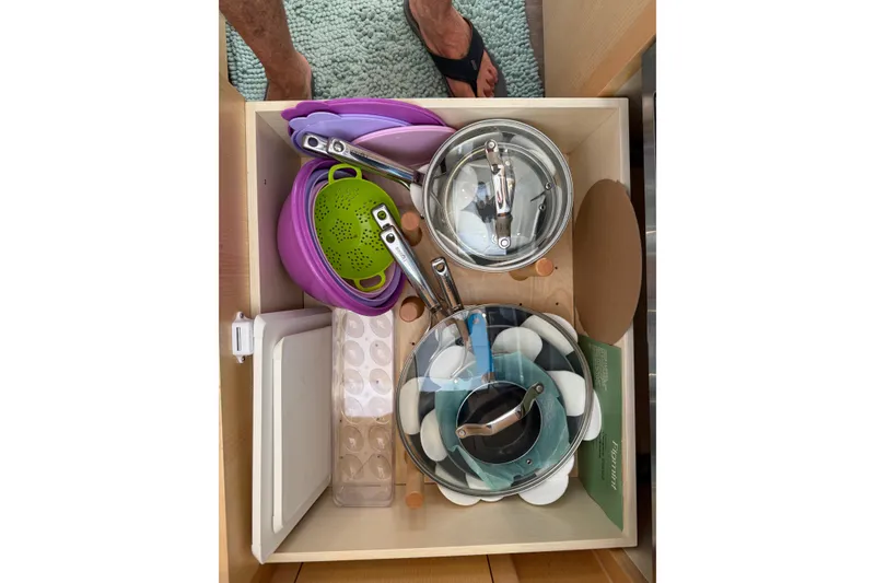 Slide: The Image of Drawer with kitchenware on Seawind 1370, 2024 model, including pots, lids, and collapsible colander. - 84