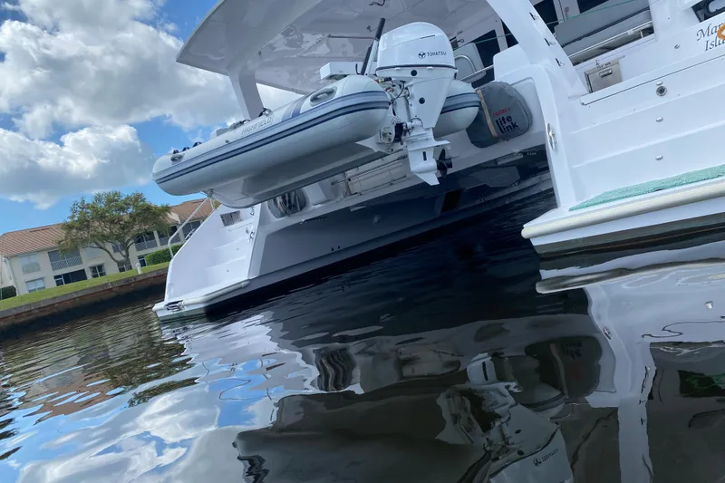 Slide: The Image of 2024 Seawind 1370 catamaran with dinghy and outboard motor on calm water. - 9