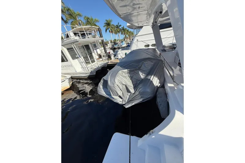 Slide: The Image of 2024 Seawind 1370 yacht docked, covered with tarp, surrounded by palm trees and other boats. - 90