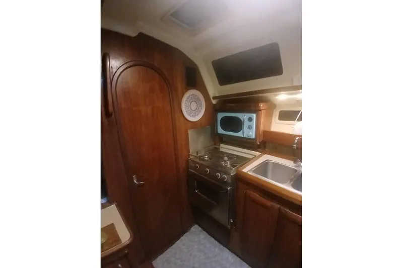 Slide: The Image of 1993 Hunter Vision 36 yacht kitchen with wood cabinetry, stove, microwave, and sink. - 24