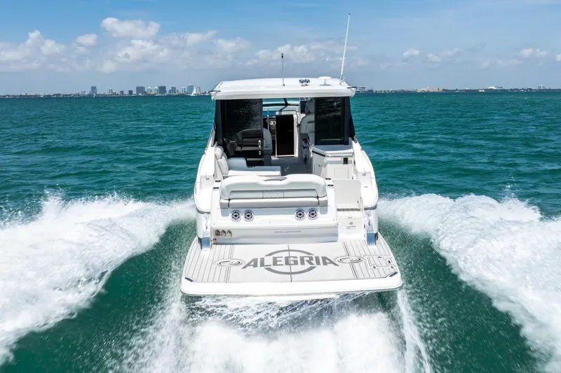 Slide: The Image of 2022 Regal 36 Grande Coupe cruising on open water, city skyline in background. - 14