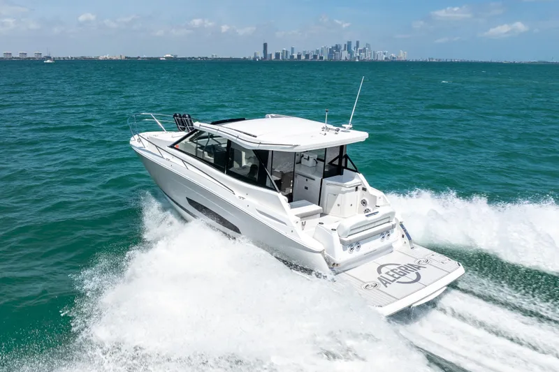 Slide: The Image of 2022 Regal 36 Grande Coupe cruising on ocean with city skyline in background. - 15