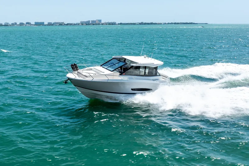 Slide: The Image of 2022 Regal 36 Grande Coupe cruising on open water, city skyline in background. - 16