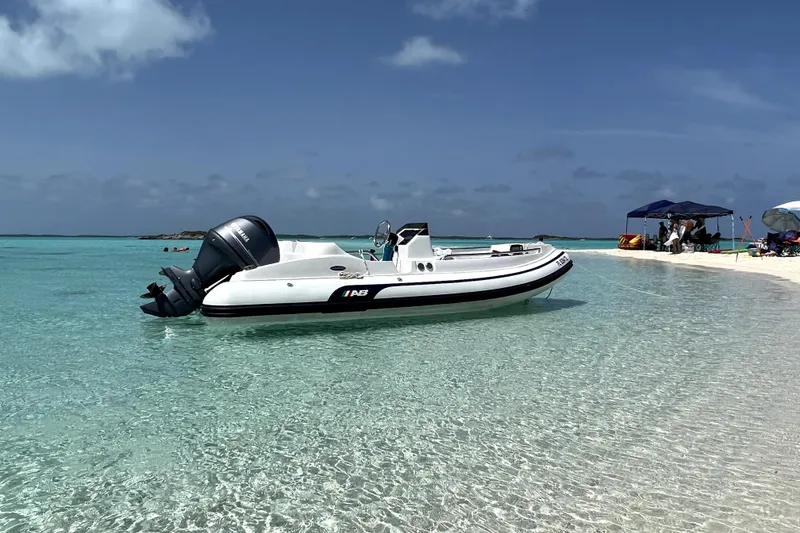Slide: The Image of 2023 AB Inflatables Nautilus 17 DLX boat anchored on clear turquoise water near a sandy beach. - 0