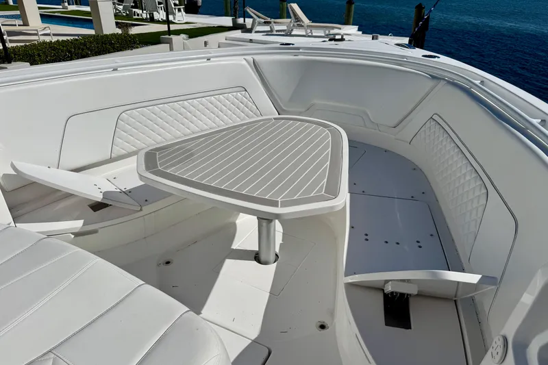 Slide: The Image of 2024 Intrepid 407 Nomad FE boat interior with white seating and table, docked by the water. - 17