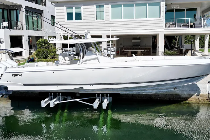 Slide: The Image of 2024 Intrepid 407 Nomad FE boat docked near modern waterfront home. - 2