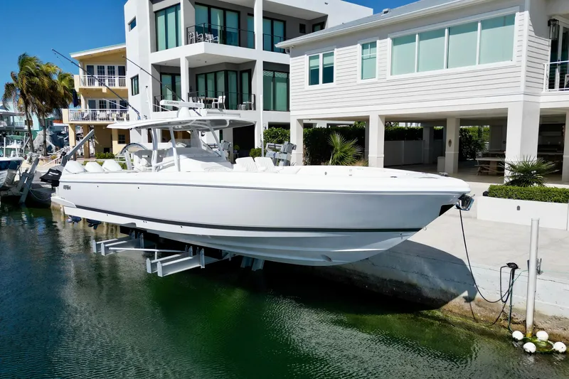 Slide: The Image of 2024 Intrepid 407 Nomad FE boat docked near modern waterfront homes. - 5