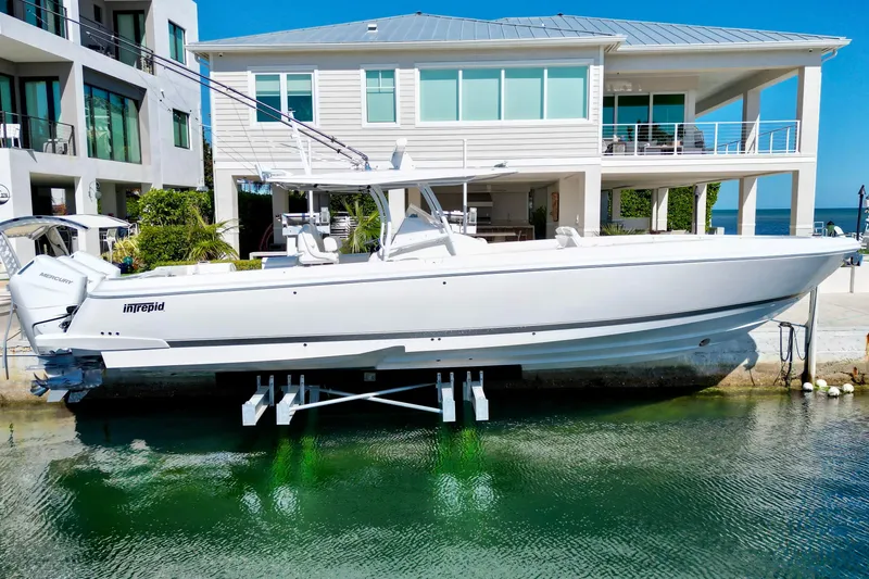 Slide: The Image of 2024 Intrepid 407 Nomad FE boat docked near modern waterfront home. - 6