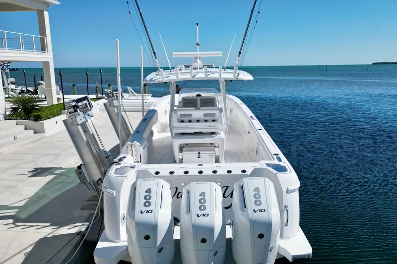 Slide: The Image of 2024 Intrepid 407 Nomad FE boat docked by the ocean, featuring triple Mercury 400 engines. - 8