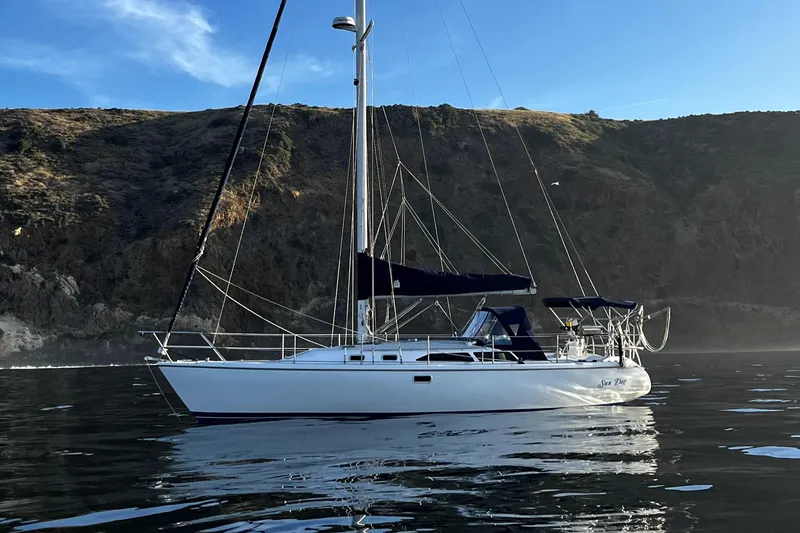 The Image of 1998 Catalina 36 MkII sailboat on calm water with scenic rocky backdrop. - 0