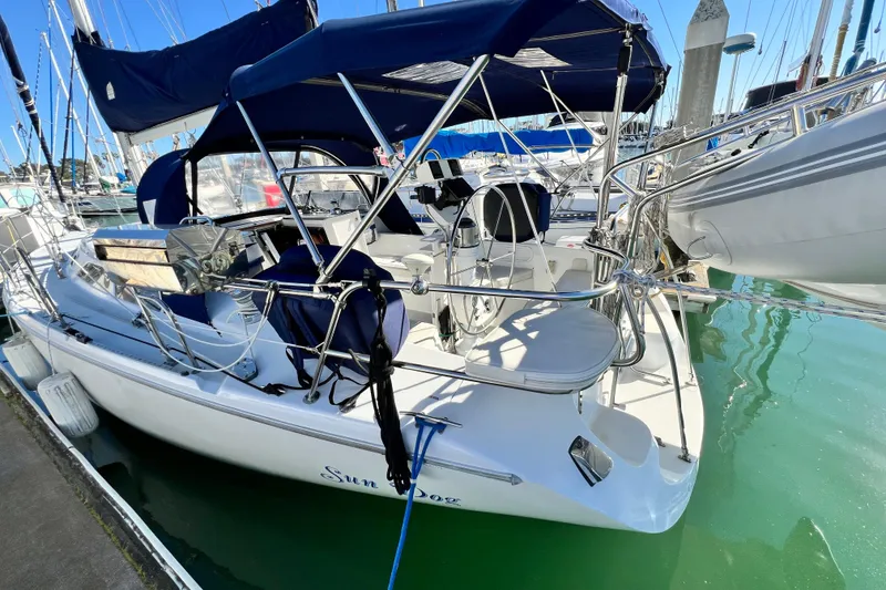 Slide: The Image of 1998 Catalina 36 MkII sailboat docked in marina, featuring blue canopy and polished deck. - 12