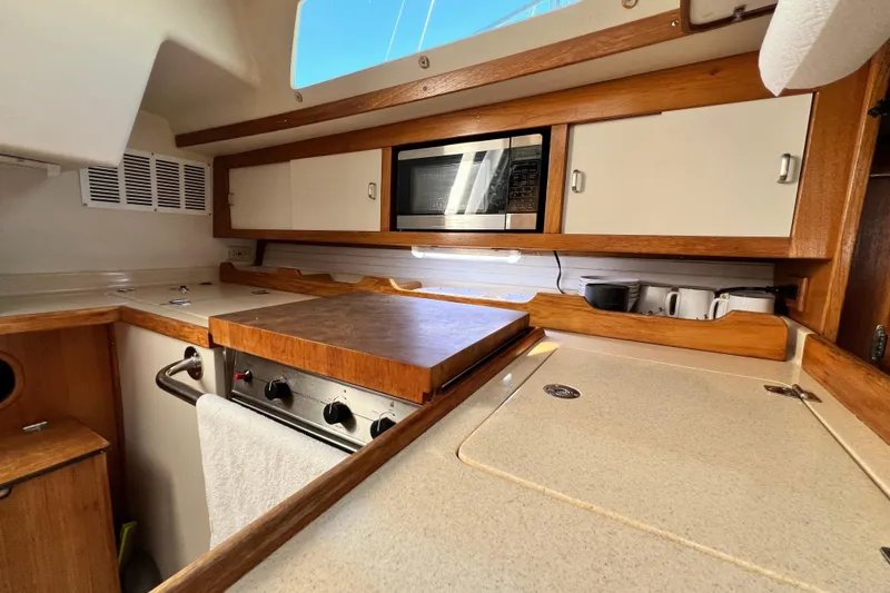 Slide: The Image of Interior view of 1998 Catalina 36 MkII yacht kitchen with stove, microwave, and wooden cabinetry. - 36