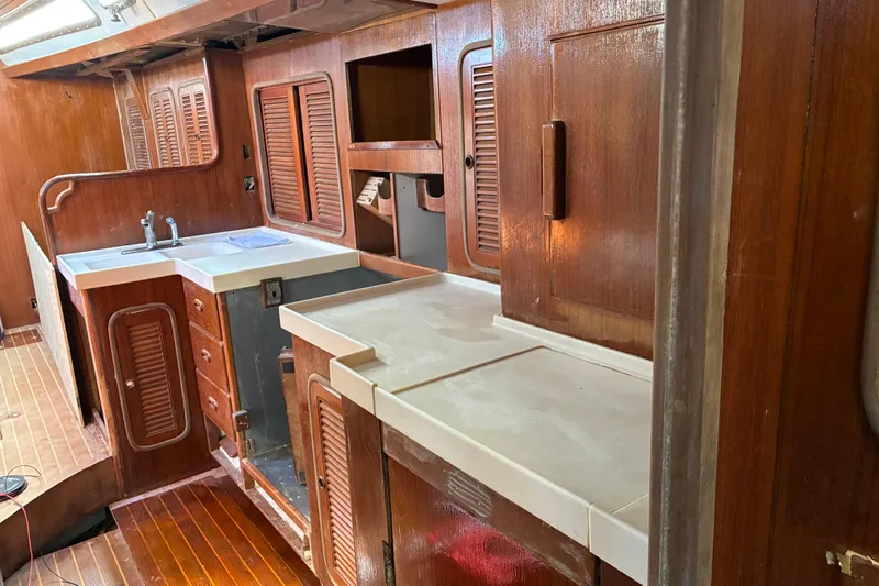 Slide: The Image of Interior of 1998 Tayana 55 yacht featuring wooden cabinetry and a compact kitchen area. - 33
