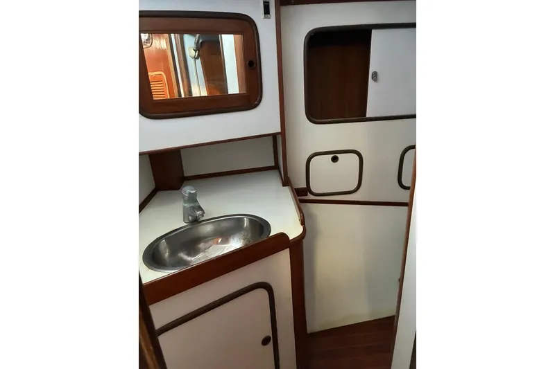 Slide: The Image of Interior of 1998 Tayana 55 yacht featuring a compact bathroom with sink and mirror. - 39